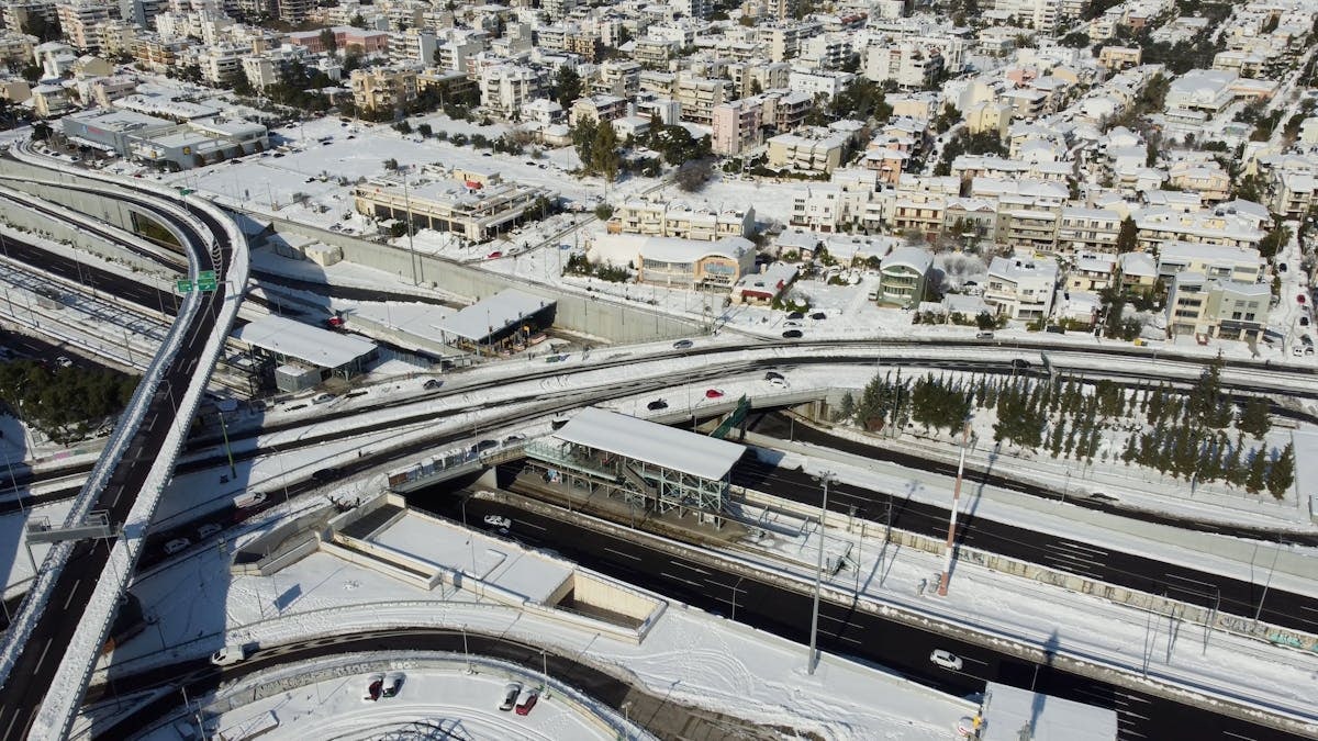 Aerial view of Athens city with snow-covered roads and buildings in winter.